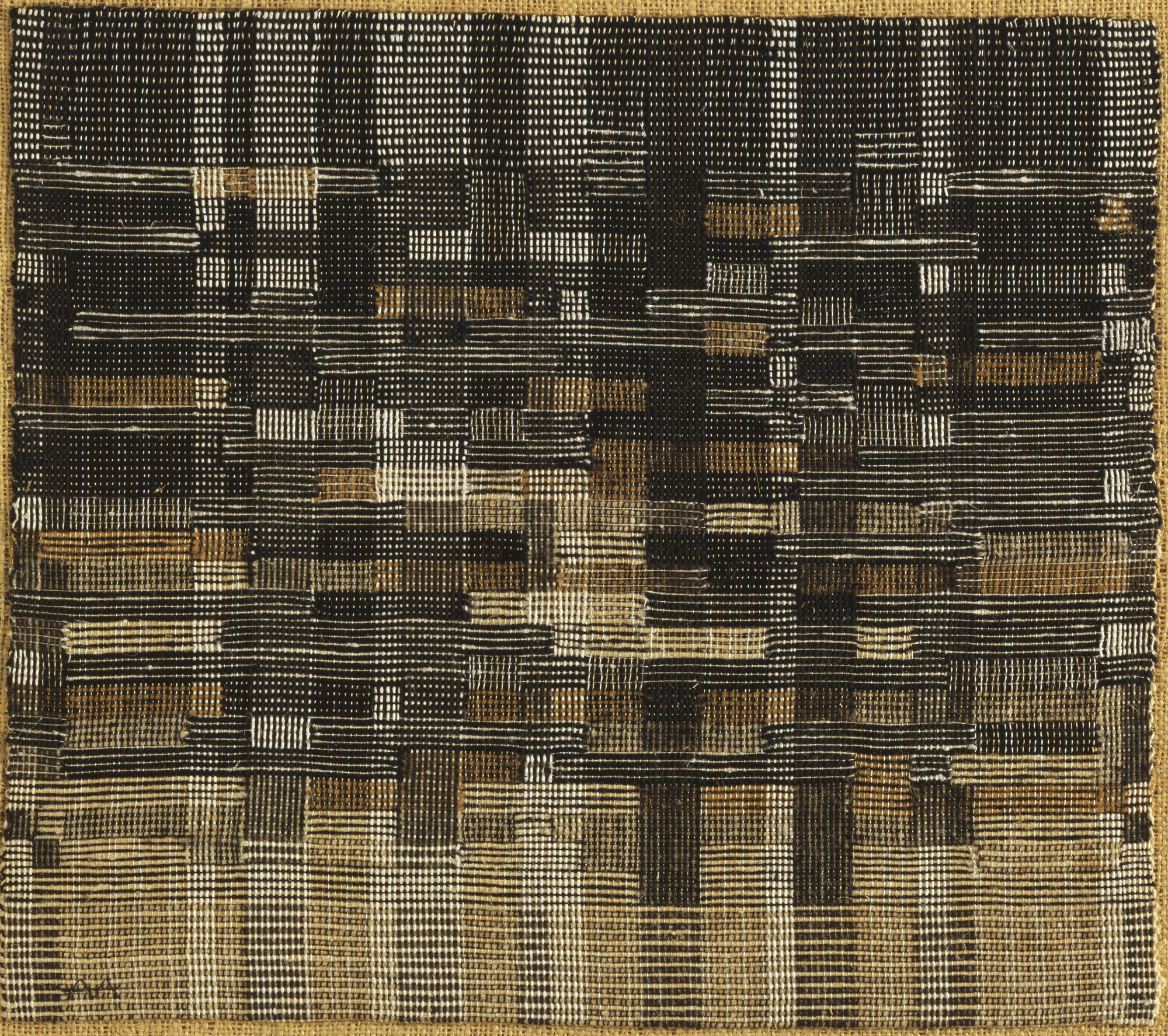 Handwoven black, ivory and ochre rectangles shift between horizontal bands and a fine checkerboard, with the textile’s edges visible.
