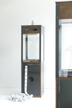 The Chaos Machine itself: the oak, steel, slate and glass crypto-jukebox, with its printed receipt roll spooling onto the floor.