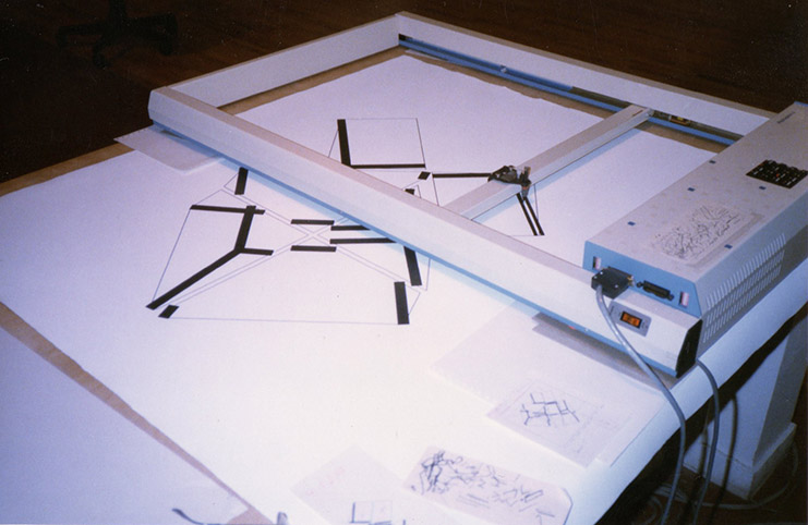 Manfred Mohr's bottomless Alpha Merics flatbed plotter drawing a large Divisibility II painting directly onto canvas in 1984, with earlier plots of the same algorithm on the table below.