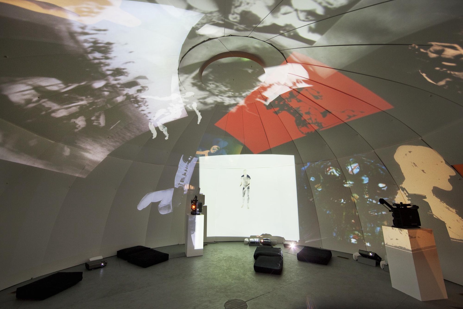 Installation view of Ghosts in the Machine at the New Museum: the interior of a projection dome with film and slide projectors on plinths throwing overlapping images across its curved walls -- the reconstruction of Stan VanDerBeek's Movie-Drome that anchored the exhibition.
