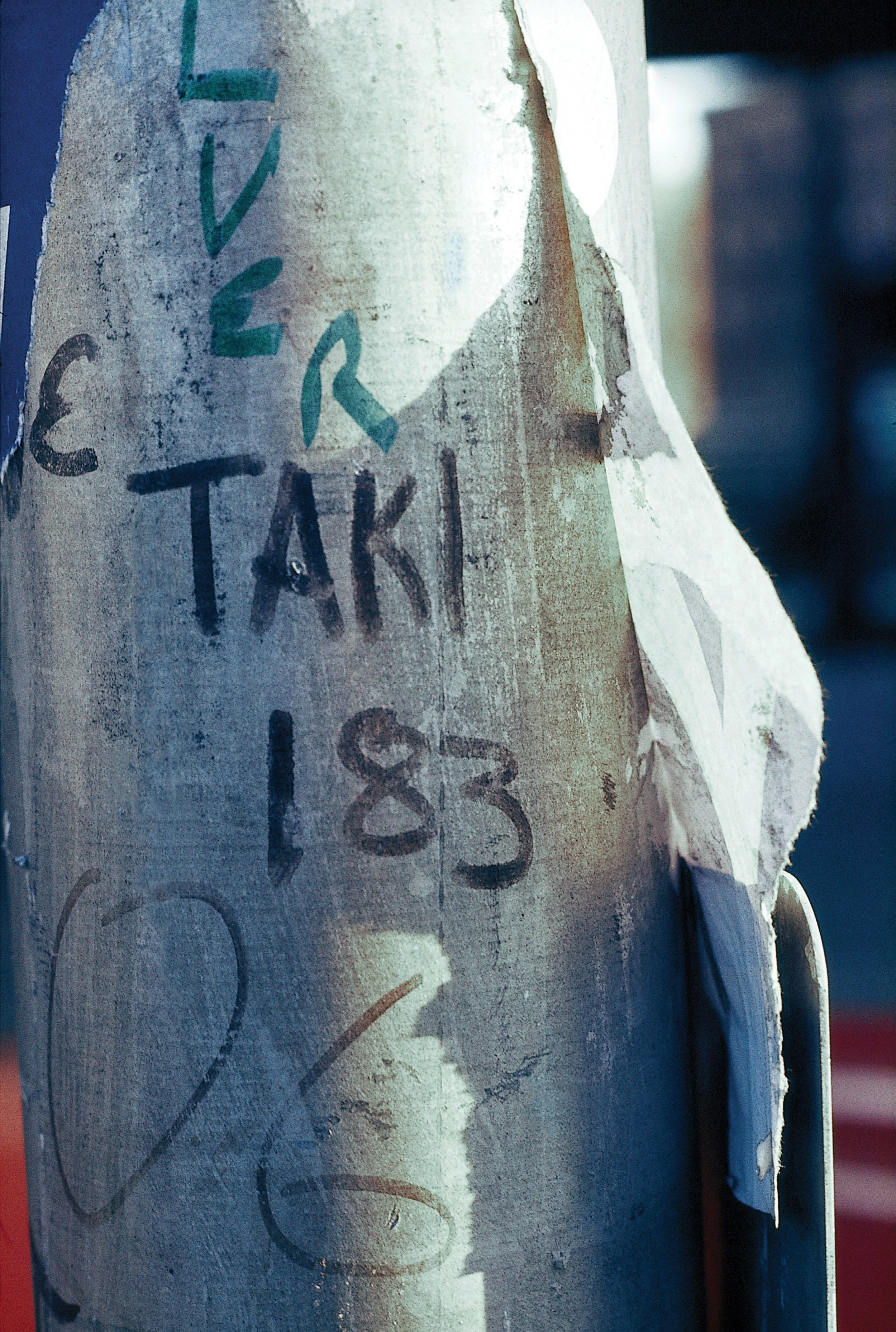 TAKI 183 written in black marker on a weathered vertical surface beside other early graffiti tags.