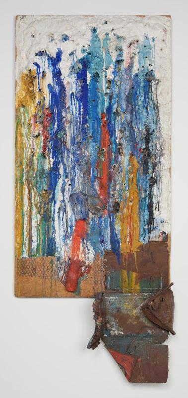 A tall white plaster assemblage streaked with blue, yellow and red paint, with embedded objects and a metal fragment extending at the lower right.