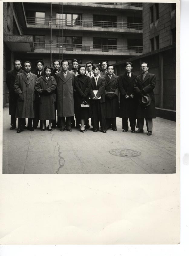A 1954 group portrait of the Jikken Kōbō members in a Tokyo courtyard — fourteen figures in winter coats, three years after the collective formed.