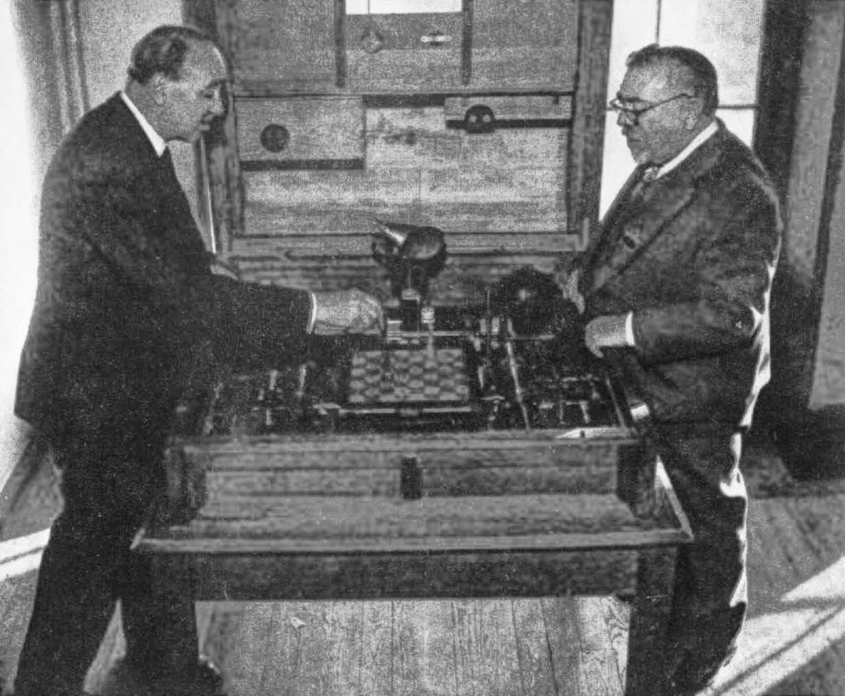 Gonzalo Torres-Quevedo (left) shows the 1920 El Ajedrecista to Norbert Wiener at the 1951 Paris conference.