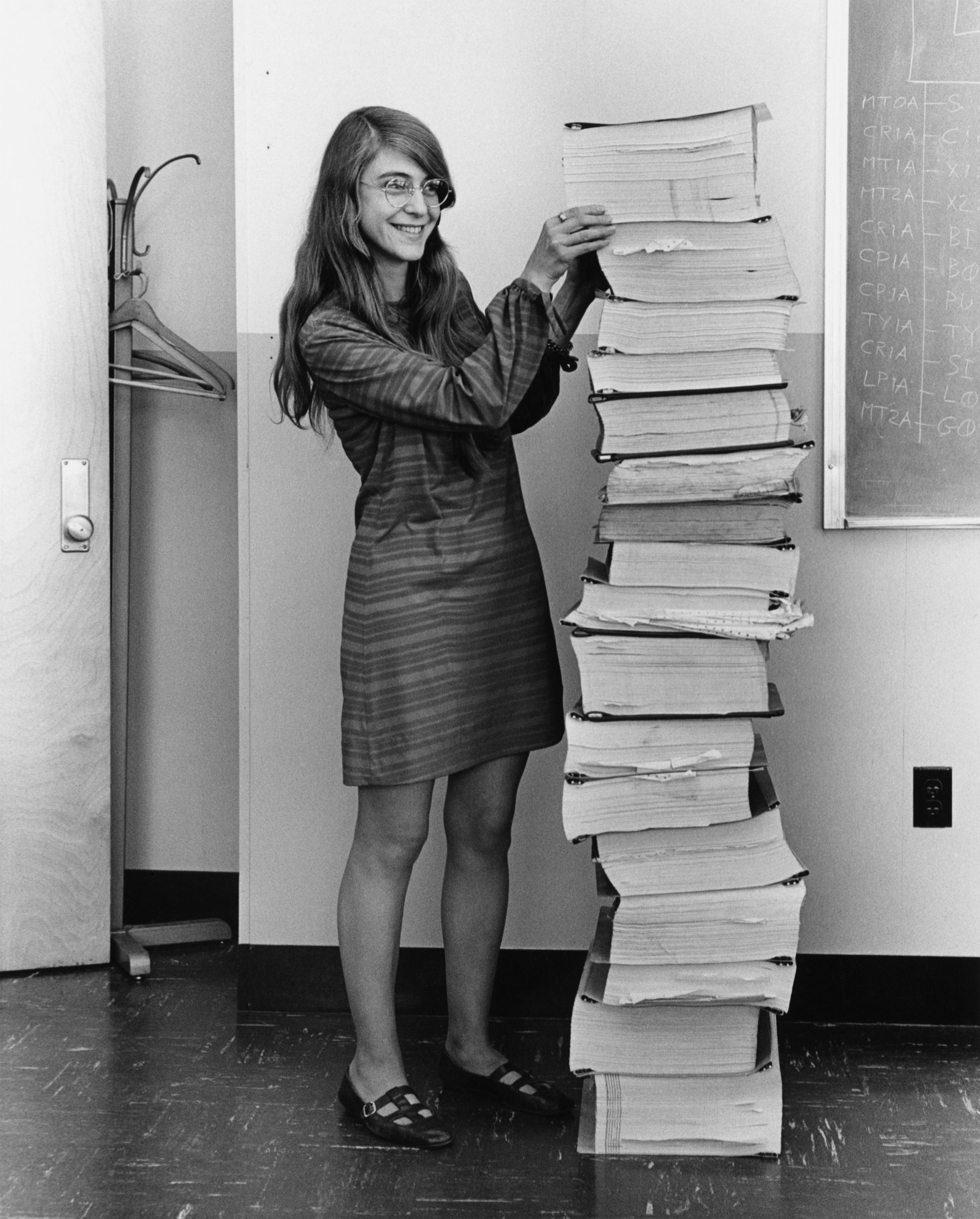 Margaret Hamilton in 1969 beside printed listings of the Apollo flight software.