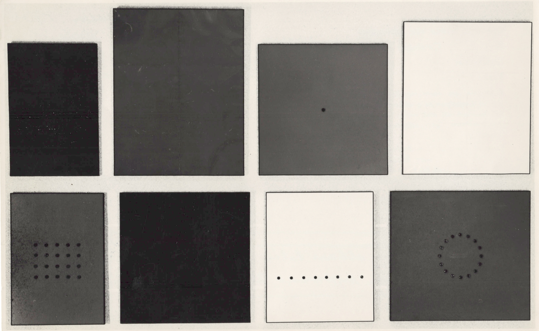 Eight monochrome rectangular and square relief works hang in two rows; several have bolts arranged as a line, a grid or a circle.