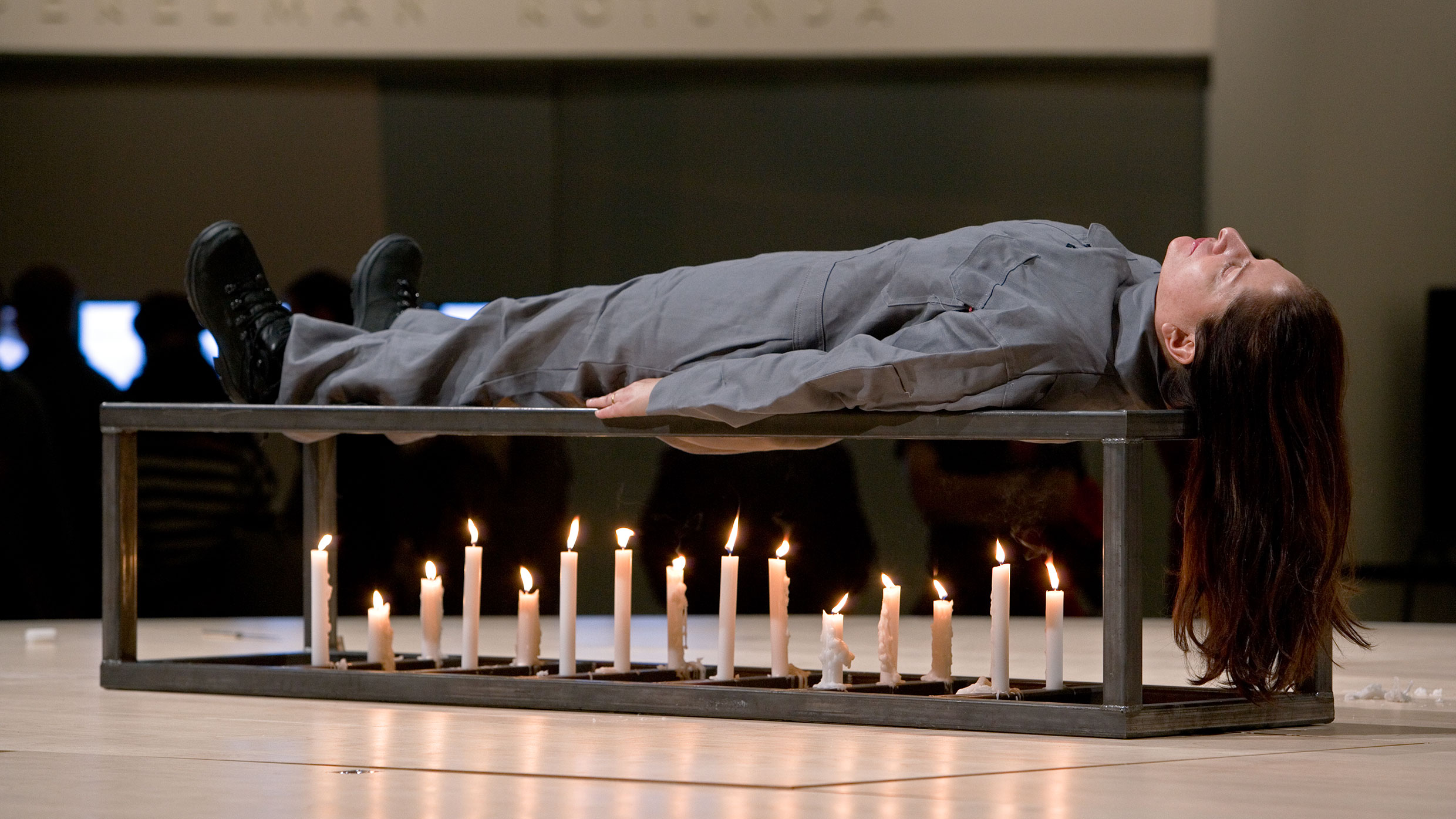 Marina Abramović lies on a metal platform above lit candles during Seven Easy Pieces.