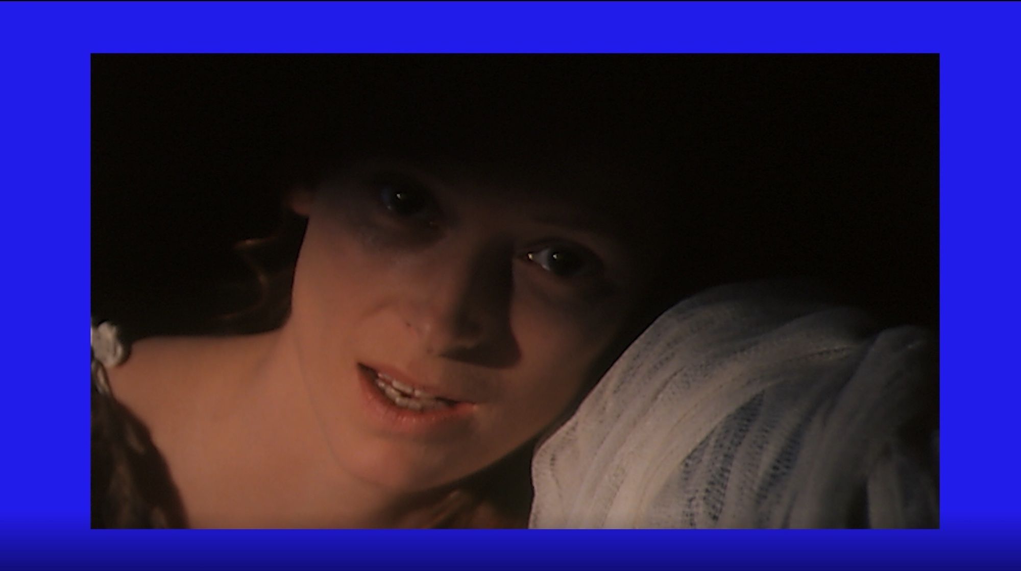 A still from Final Transformation #2: a film image of Tilda Swinton within a vivid blue border.