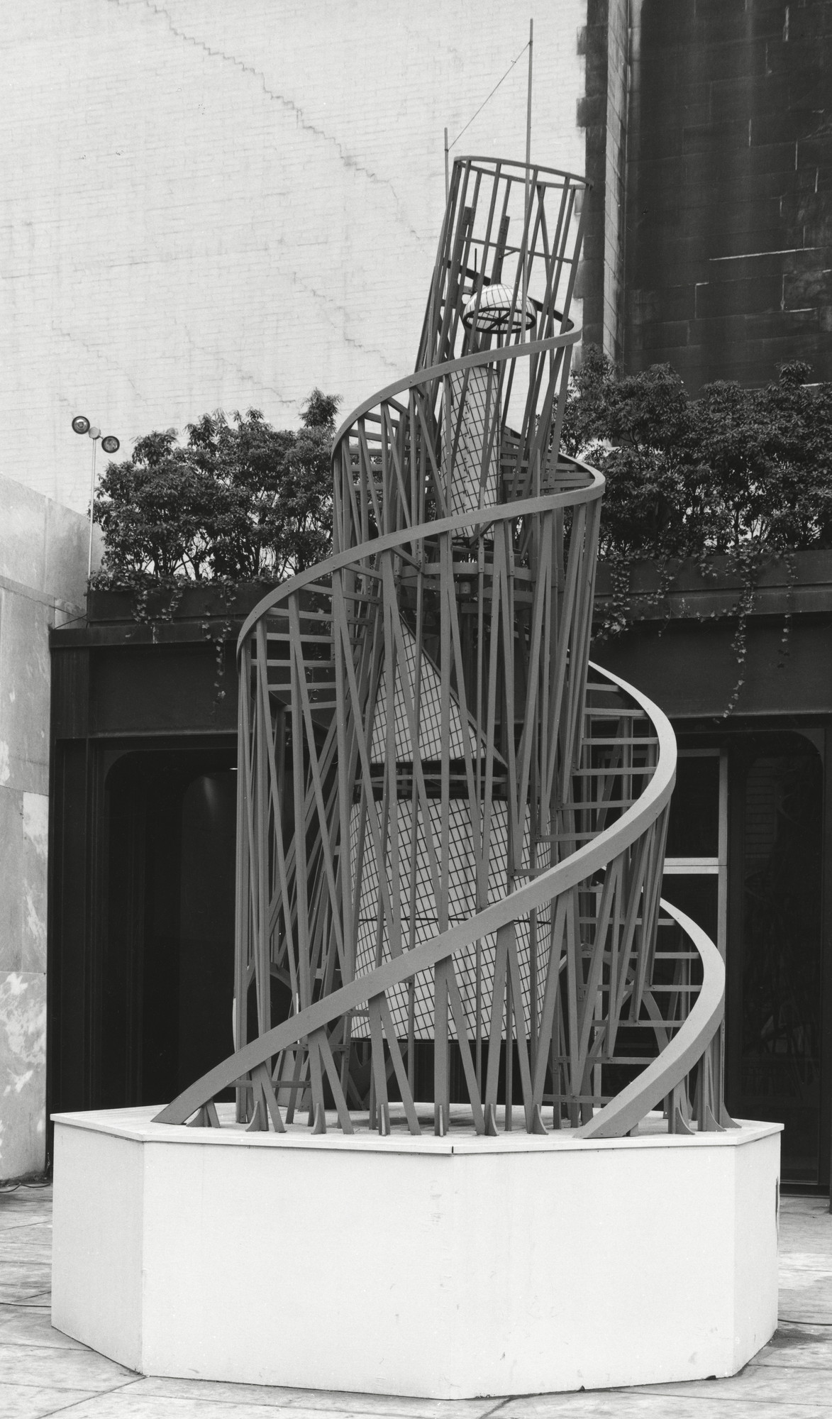 Installation view of The Machine at MoMA, showing the tall spiral reconstruction of Vladimir Tatlin's Monument to the Third International standing in the museum's sculpture garden.