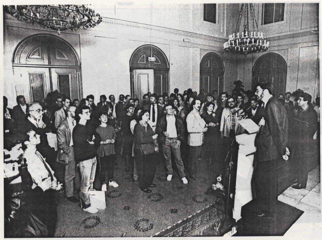A black-and-white photograph of the opening reception of the First International Symposium on Electronic Art in Utrecht city hall in 1988, with several hundred delegates facing a speaker at a lectern beneath the chandeliers.