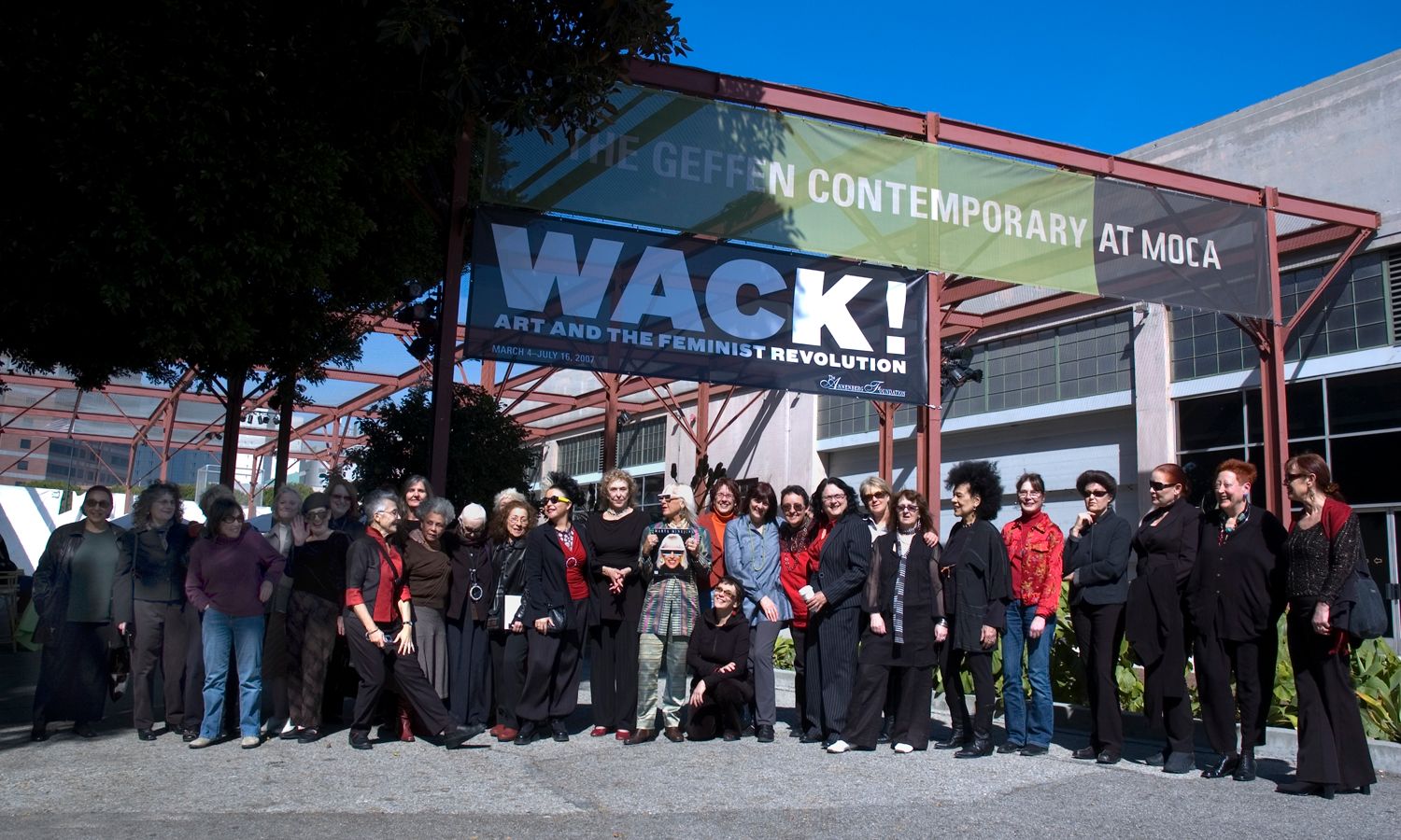 Some thirty of the exhibiting artists gathered outdoors beneath the WACK! Art and the Feminist Revolution banner at the entrance to The Geffen Contemporary at MOCA, 2007.